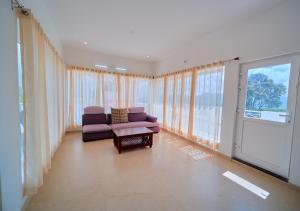 a living room with a couch and a table and windows at Cucuu Nest Villa Coonoor by VOYE HOMES - Surrounded by Tea Plantations in Coonoor