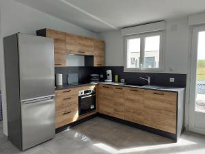 a kitchen with a stainless steel refrigerator and wooden cabinets at Les jonquilles in Forest-Montiers