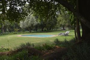 a picnic table and two chairs in a park at Bridgewaters Horse Park Poolside Rondawel in Hekpoort