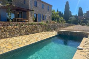 una casa con piscina junto a una pared de piedra en Provençal Escape, en Montauroux