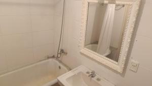a white bathroom with a tub and a mirror at FincaMora in Colonia del Sacramento