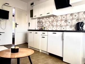 a kitchen with white cabinets and a table at Familly Apartament 6 in Międzyzdroje