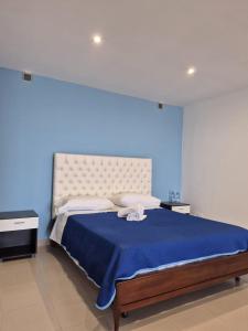 une chambre avec un grand lit avec un mur bleu dans l'établissement Belvedere di Ciro', à Cirò