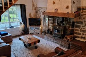 a living room with a fireplace and a couch and a table at 3 Bed Cottage Sleeps 6 - Enclosed Patio -Fireplace in Beaucoudray