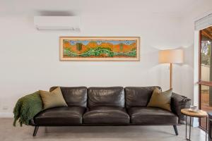 a leather couch in a living room with a picture on the wall at Chrissie's Cottage in Dunsborough