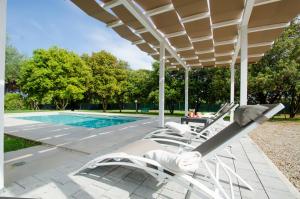 a group of lounge chairs under a pergola next to a pool at Villa Asia Deluxe in Castiglione del Lago
