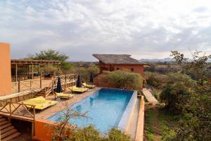 Una piscina con tumbonas y una casa. en Escarpment Luxury Lodge Manyara, en Mto wa Mbu