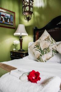 a bedroom with a white bed with a red rose on it at Lamon Guesthouse in Kroonstad