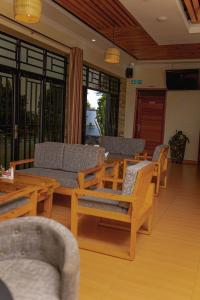 a living room with wooden chairs and tables and windows at RP Gorilla Guest & Coffee in Taba