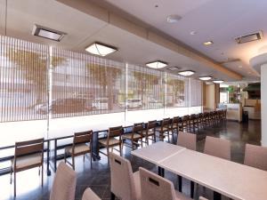 a dining room with tables and chairs and a large window at APA Hotel Kokura Ekimae in Kitakyushu