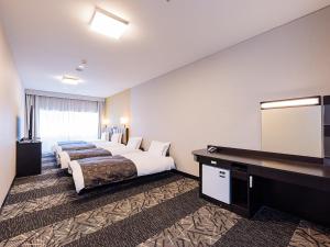 a hotel room with two beds and a flat screen tv at APA Hotel Kokura Ekimae in Kitakyushu +51 photos