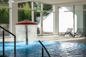 Una piscina con una fuente en un edificio con sillas. en Schneeeule 209, en Granzow