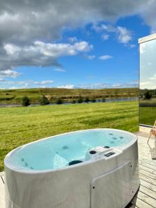 a hot tub on a deck with a view of a field at Nest Retreat Iceland in Hella