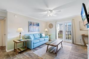 un salon avec un canapé bleu et une table dans l'établissement Colony Club Condos, à Gulf Shores