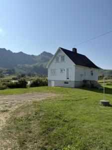 a white barn on a field with mountains in the background at Peaceful retreat in Lofoten in Sennesvik