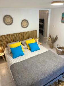 a bedroom with a bed with blue and yellow pillows at Esprit CAP FERRET in Puget
