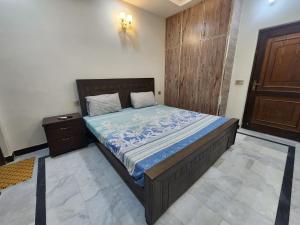a bedroom with a bed with a blue comforter at Guest House & Apartments Johar Town near Emporium & Expo in Lahore