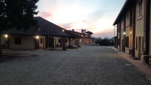 an empty road between buildings with a sunset in the background at FARM-AgriHotel in Certosa di Pavia
