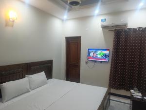 a bedroom with a bed and a tv on the wall at Guest House & Apartments Johar Town near Emporium & Expo in Lahore