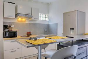 a kitchen with white cabinets and a counter with a sink at Ti Kaz Maloya - Saint Paul in Saint-Paul