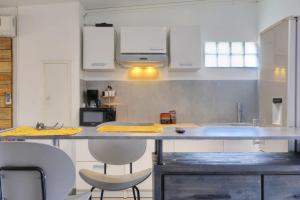 a kitchen with white cabinets and a counter with chairs at Ti Kaz Maloya - Saint Paul in Saint-Paul +22 photos