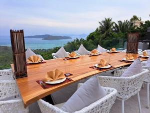 a long wooden table with chairs and a view of the ocean at Villanirvanasamui 