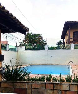 a swimming pool in front of a white wall at Casa Rocha in Porto Seguro
