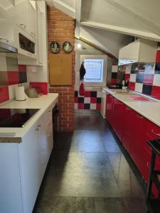 a kitchen with red and white cabinets and a brick wall at Katata Apartment Spacious House Floor with Terraces, 3 Bedrooms, Parking,Wi-Fi in Podgorica
