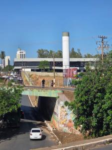 een witte auto die onder een brug in een stad rijdt bij Hotel Danubio in Cuiabá