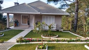 a small house with flowers in the front yard at Casa Zanata in Gramado +25 photos
