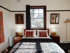 a bedroom with a bed with two lamps and a window at Women Only Guesthouse in Mullumbimby