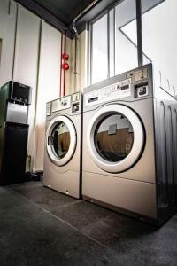 two washing machines sitting next to each other in a room at GUSTI Backpackers Capsule Hostel Singapore in Singapore