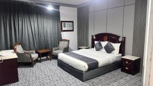a hotel room with a bed and a desk and chairs at فندق كراون نجران الفندقيه in Najran