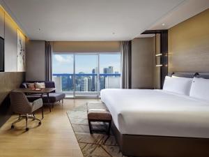 a hotel room with a large bed and a desk at Swissotel The Stamford Singapore in Singapore