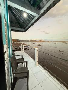 a balcony with two chairs and a view of the water at Komodo Wisata Homestay in Komodo