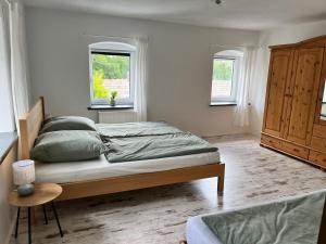 ein Schlafzimmer mit einem Bett und zwei Fenstern in der Unterkunft Zum alten Rittergut in Malschwitz