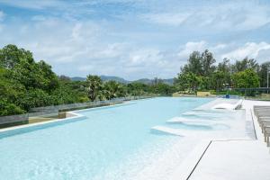 a large swimming pool with chairs and trees at Beachside Residences by NLA in Bang Tao Beach