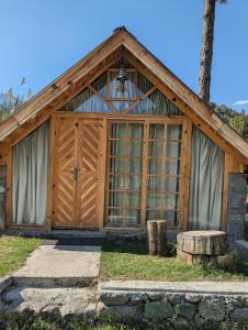 a wooden barn with a large glass door at StoneWood Cottage At Country Club Resorts Balakot in Bālākot