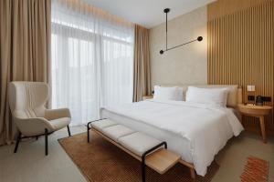 a bedroom with a large white bed and a chair at SIRO Boka Place in Tivat