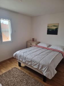 a white bedroom with a bed and a window at Maison Gardelle in Thiers +1 photo