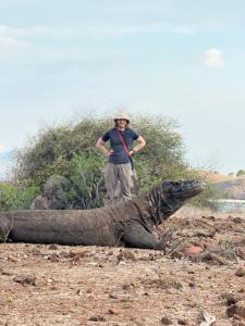 a man standing next to an alligator on a field at Komodo Wisata Homestay in Komodo +2 photos