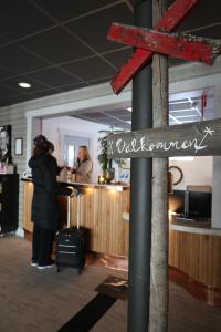 a woman standing in front of a counter with a sign at Hotell Klövsjöfjäll in Klövsjö