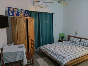 a bedroom with a bed and a dresser and a table at Le Hublot in Cotonou