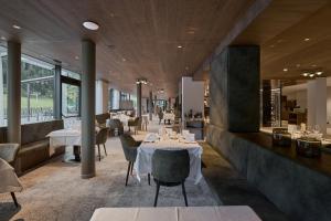 a restaurant with white tables and chairs and windows at Berghotel in Racines