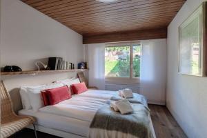 a bedroom with a white bed with red pillows and a window at Prada Laax by Quokka 360 - building with sauna in Laax