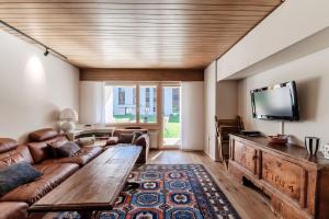 a living room with a couch and a flat screen tv at Prada Laax by Quokka 360 - Alpine Residence with Shared Sauna in Laax