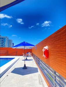un parasol bleu posé sur un muret de briques à côté d'une piscine dans l'établissement Flat Completo - Praia de Jatiuca, à Maceió