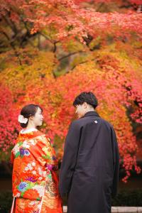 a man and a woman standing in front of a tree at Oukai Villa Izumi in Izumi