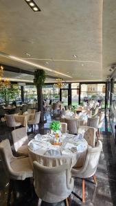 a restaurant with white tables and chairs and windows at Hotel RAS Pazarište in Novi Pazar