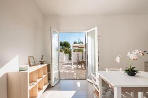 une cuisine blanche avec une porte menant à une terrasse dans l'établissement Arvèa – Lux Coastal Essence, à Torre Lapillo